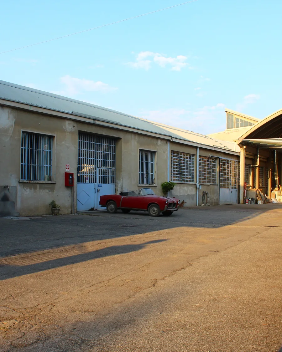 Cortile della carrozzeria Galimberti a Giussano con un'auto d'epoca rossa davanti ai capannoni